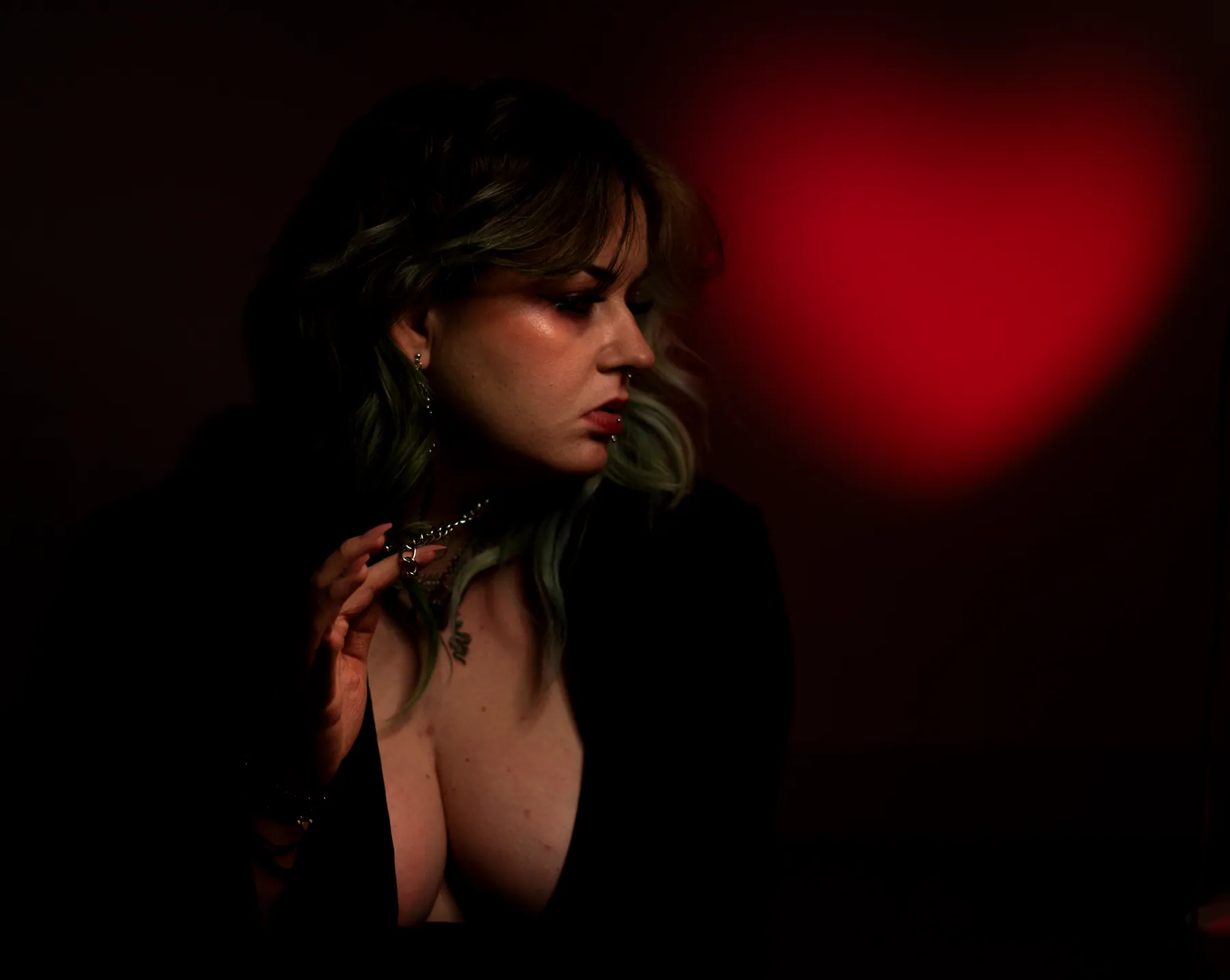 Dark portrait of a person in profile against a glowing red heart-shaped light